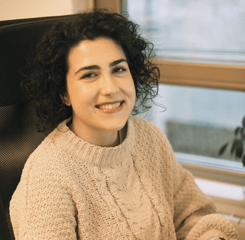 A woman sitting on a chair smiles at the camera