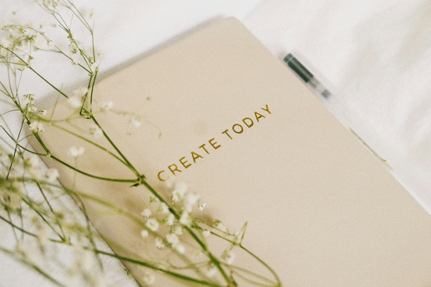 Close-up shot of a planner with a message next to a pen and some flowers