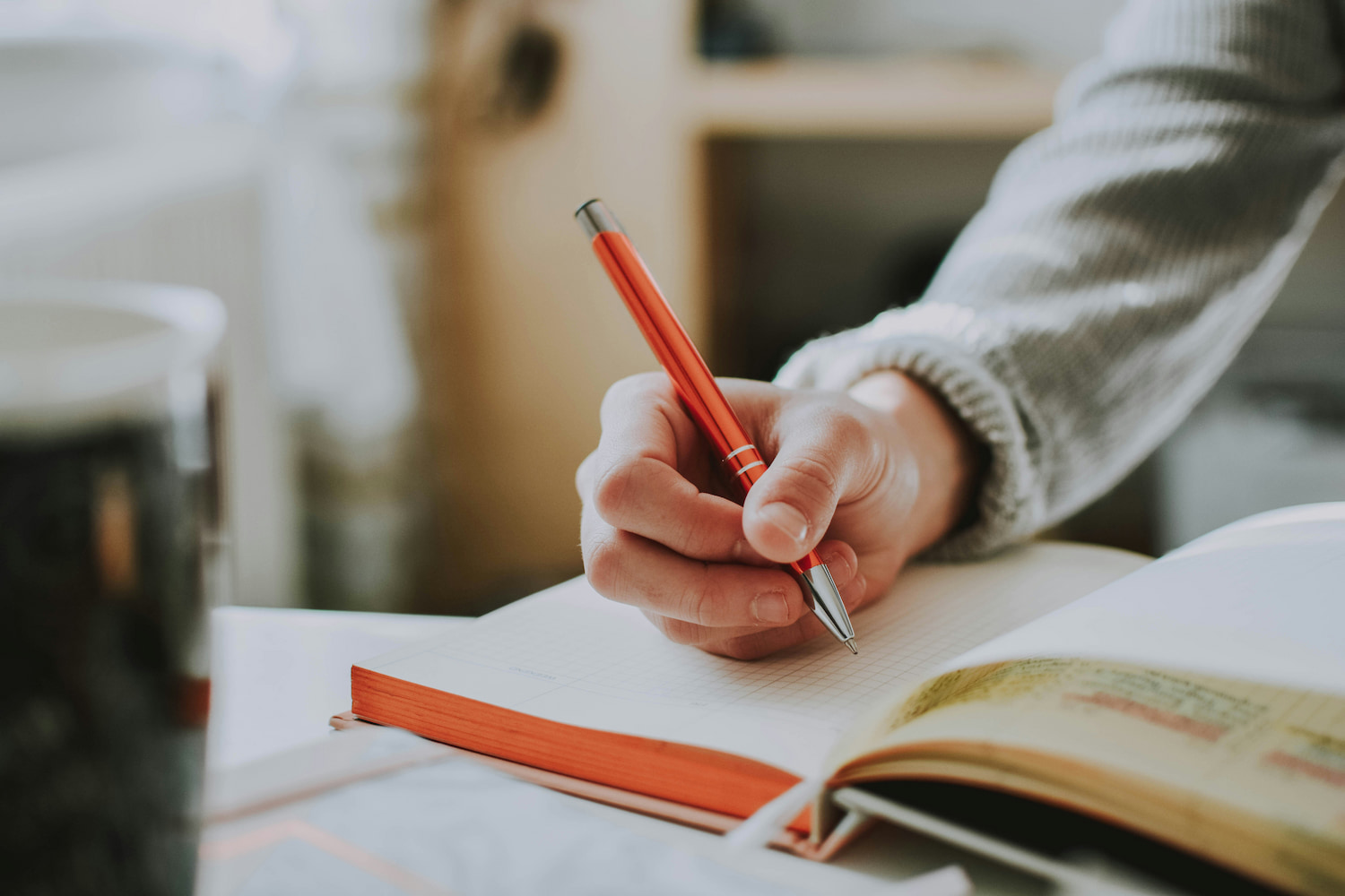 A woman’s hand about to write on a blank planner with a pen