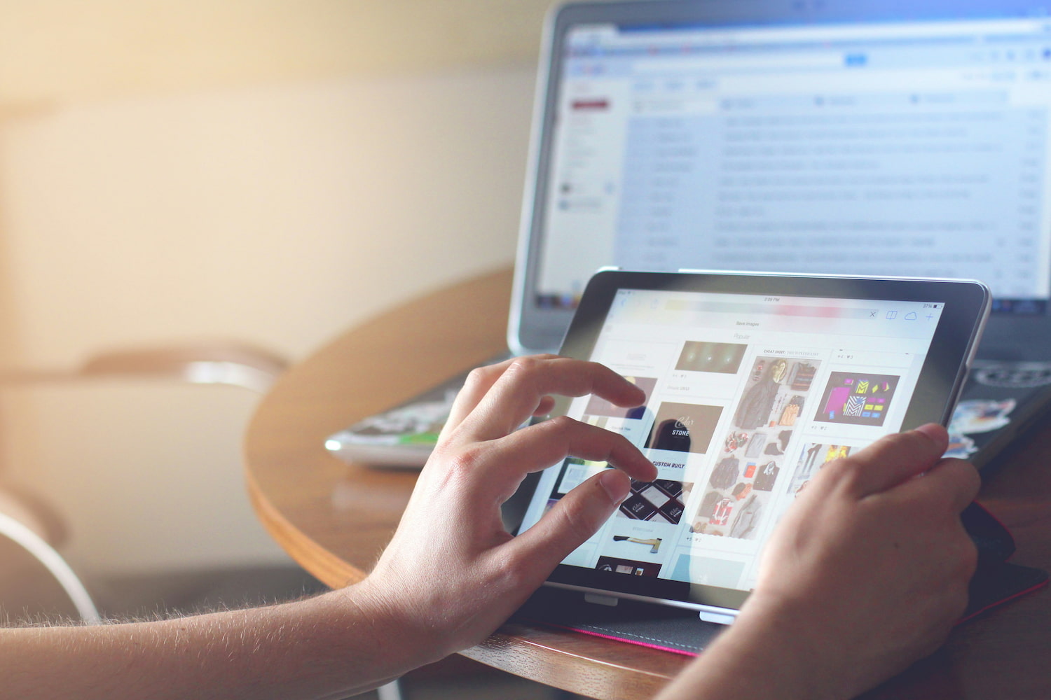Two hands are scrolling through images on a tablet screen